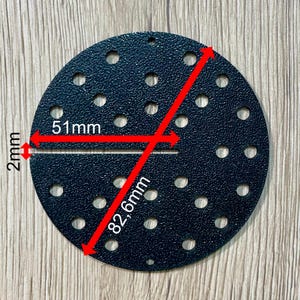 Può includere: Un disco abrasivo circolare nero con diversi piccoli fori. Il disco ha un diametro di 82,6 mm e una larghezza di 2 mm. Il diametro del disco è di 51 mm.