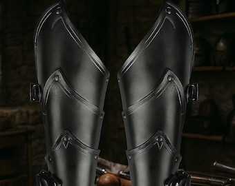 May include: Pair of black arm guards with riveted accents and buckle closures. The armor appears to be made of a durable material, possibly metal or hardened leather. The design suggests a medieval or fantasy theme.