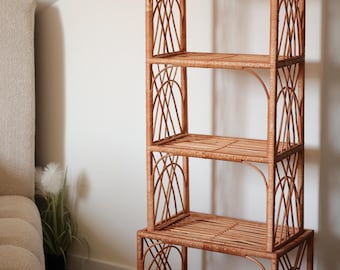 Pode incluir: Uma estante alta arqueada em rattan com quatro prateleiras. O vime castanho natural tem um design aberto com padrões decorativos tecidos nas laterais. As prateleiras são retangulares e oferecem amplo espaço de armazenamento.