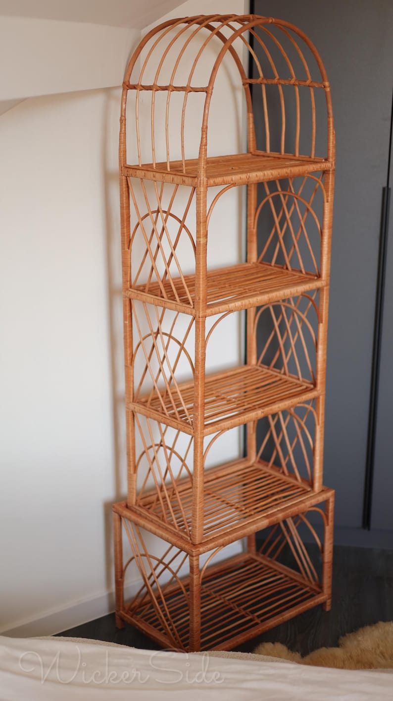 May include: A tall, freestanding wicker shelf unit with an arched top and multiple shelves. The natural brown wicker is woven into a lattice design on the sides and back, creating an open and airy storage solution. The unit has five shelves and is approximately 60 inches tall.