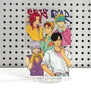 May include: A clear acrylic stand featuring a colorful anime-style illustration of six male figures. The artwork includes the text "2009 ATAR" at the top. The figures are depicted in various outfits and hairstyles, with a light blue and purple background.