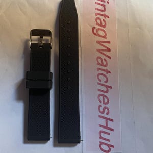 May include: Two-piece black watch strap with a textured surface. The strap includes a gold-colored buckle. The text "VintageWatchesHub" is visible on a white and pink label.