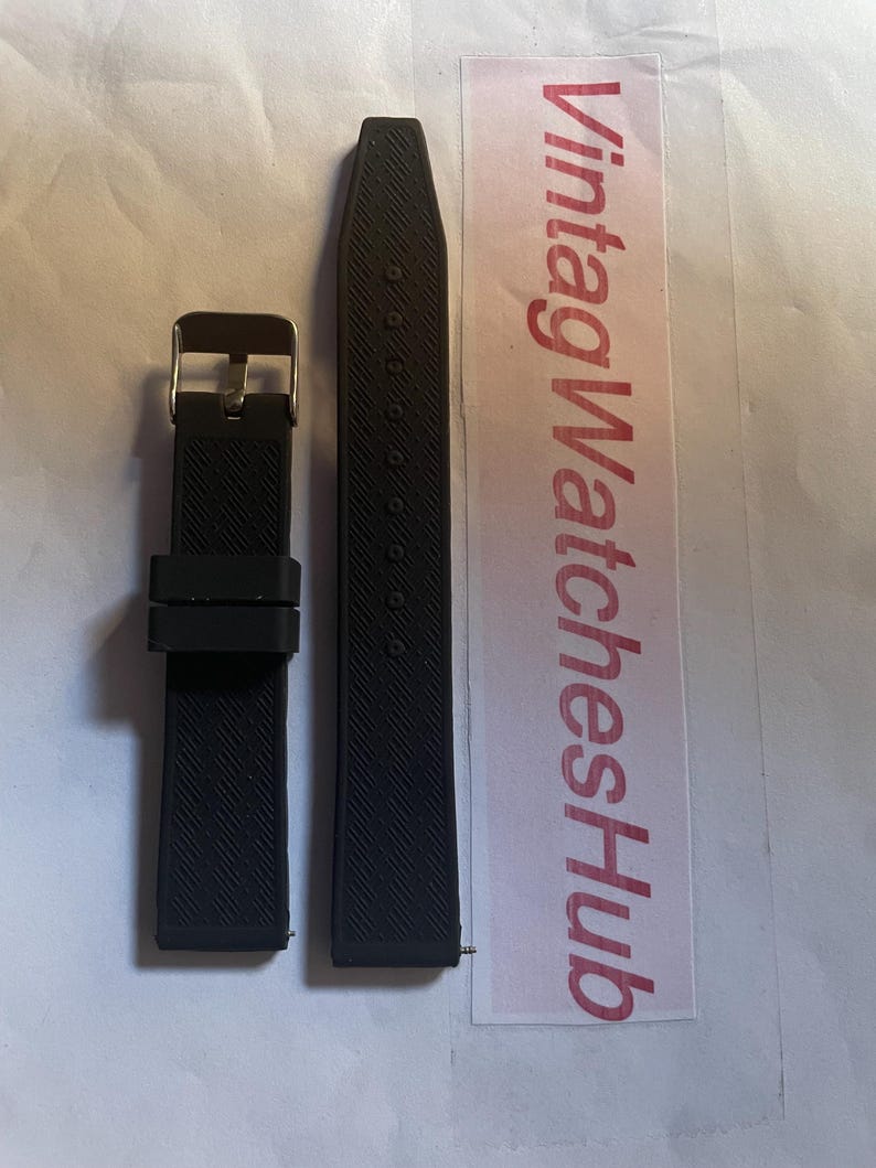 May include: Two-piece black watch strap with a textured surface. The strap includes a gold-colored buckle. The text "VintageWatchesHub" is visible on a white and pink label.