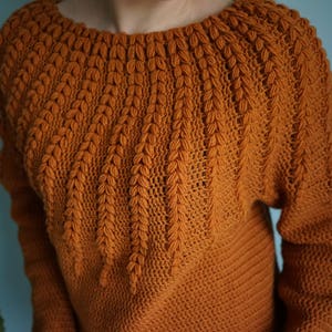 May include: A brown crocheted sweater with a unique leaf-shaped stitch pattern around the neckline.