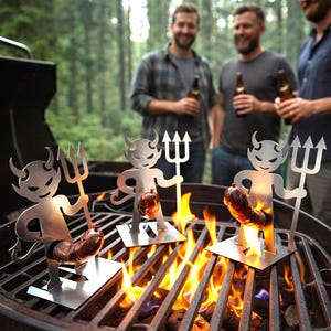 Può includere: Tre utensili da barbecue a forma di diavolo in metallo, ciascuno con una salsiccia sopra una griglia a carbone. I diavoli hanno le corna e tengono dei tridenti. Le fiamme sono visibili sotto le griglie del barbecue. Tre persone sono sullo sfondo, che tengono bottiglie.