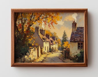 May include: A framed painting depicts a quaint village street scene. The artwork features a row of cream-colored houses with chimneys, a cobblestone road, and trees with vibrant yellow and orange foliage. The painting is set in a wooden frame.