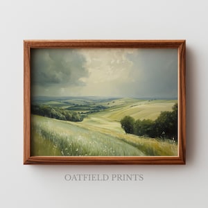 May include: A framed landscape painting shows rolling green hills beneath a cloudy sky. The artwork, in a wooden frame, features a field of tall grass in the foreground and the text "OATFIELD PRINTS" at the bottom.