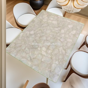 May include: A rectangular table with a light-coloured, textured surface, surrounded by white chairs with wooden legs. The table's surface has a mosaic-like pattern. The text "BreezeCraftsStudio" is visible on the table.