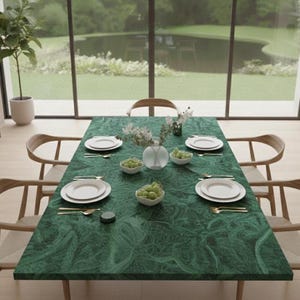 Puede incluir: Una mesa de comedor preparada para una comida. La mesa tiene una superficie verde estampada y está puesta con platos blancos, cubiertos y pequeños cuencos de uvas verdes. Sillas de madera rodean la mesa y un jarrón de flores está en el centro.