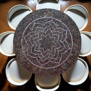 Könnte beinhalten: Draufsicht auf einen runden Esstisch mit Mosaikplatte und floralem Design. Der Tisch ist von sechs weißen Stühlen mit goldenen Zierleisten umgeben, die auf einem Holzboden stehen. Die Tischoberfläche hat eine schimmernde, irisierende Qualität.