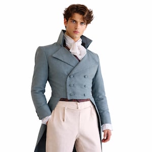 May include: A pale blue double-breasted tailcoat with a high collar and matching buttons. The coat is worn with cream-coloured trousers and a white ruffled shirt. The outfit is reminiscent of historical formal wear.