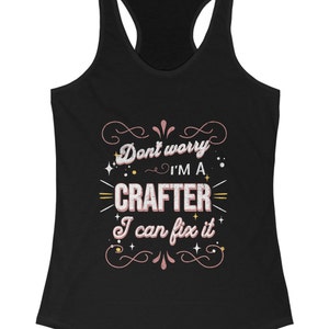 May include: Black racerback tank top with the text "Don't worry I'm a CRAFTER I can fix it" in a decorative font. The text is in white, gold, and pink. The tank top has a scoop neck and a racerback design.