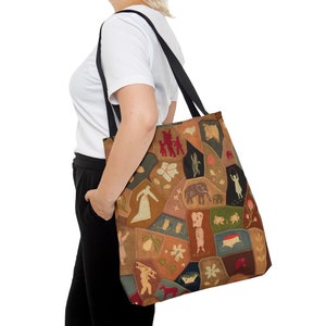May include: A brown and tan tote bag with a patchwork design featuring various embroidered images, including a family, a butterfly, an elephant, a bird, a flower, and a ladder. The bag has black straps.
