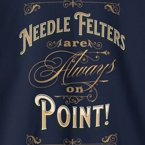 May include: A navy blue t-shirt with gold lettering that reads "Needle Felters are Always on Point!" The text is in a decorative font with flourishes.