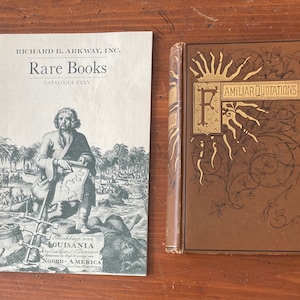 May include: A vintage book titled "Familiar Quotations" with a decorative gold letter "F" and ornate floral designs on the cover. The book is bound in brown leather and has a gold-colored spine.