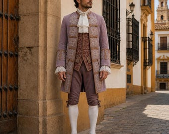 May include: A lavender-colored, long coat with ornate gold embroidery, worn over a patterned vest and matching breeches. The outfit includes a white ruffled cravat, white stockings, and gold shoes. The ensemble is reminiscent of historical formal wear.