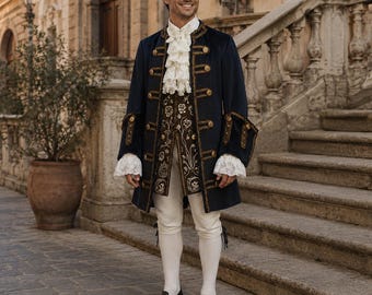 May include: A man wearing a navy blue coat with gold buttons and trim, a ruffled white shirt, and a decorative vest. He is also wearing white breeches, black shoes with gold buckles, and white stockings. The outfit is reminiscent of historical attire.