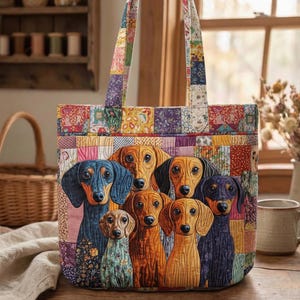 Può includere: Una borsa tote trapuntata con un colorato design patchwork e un gruppo di bassotti. La borsa ha una forma rettangolare con due manici e un'illustrazione dettagliata dei cani in vari colori, tra cui blu, marrone e nero.