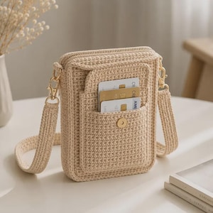 Può includere: Una borsa a tracolla in uncinetto color beige con uno scomparto principale rettangolare con chiusura a zip, una tasca frontale esterna con bottone magnetico e una tracolla in uncinetto abbinata fissata con moschettoni in metallo dorato.