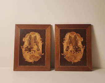 Könnte beinhalten: Ein Paar rechteckige Wandtafeln aus Holz mit aufwendiger Intarsienarbeit. Jede Tafel zeigt eine Szene aus hellem Holz mit einer an einem Tisch sitzenden Person in einem drapierten Innenraum vor einem dunkelbraunen Holzhintergrund.