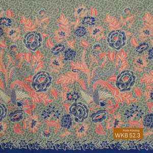 Op de afbeelding: Een stof met een herhalend bloemenpatroon in blauw, koraal en crème op een grijze achtergrond. Het ontwerp toont grote, gestileerde bloemen en bladeren. De onderrand heeft een blauwe rand met bloemendetails. De tekst "WKB 52.3" is zichtbaar.