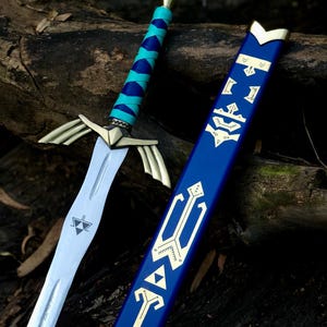 May include: A detailed image of a fantasy sword with a silver blade and gold accents. The hilt is wrapped in blue and teal leather. The blue scabbard features gold geometric designs. The sword is resting on a dark wooden surface.
