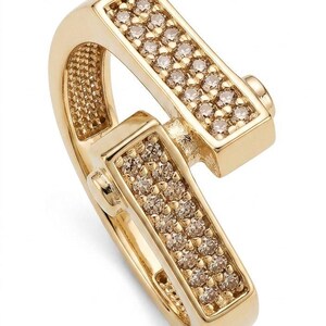 May include: A gold-colored ring with a unique design. The ring features two rectangular sections, each encrusted with small, sparkling stones. The ring's band curves gracefully, connecting the two sections. A stylish piece of jewelry.