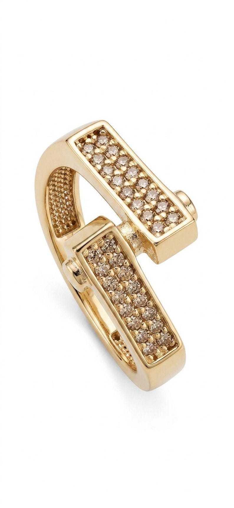 May include: A gold-colored ring with a unique design. The ring features two rectangular sections, each encrusted with small, sparkling stones. The ring's band curves gracefully, connecting the two sections. A stylish piece of jewelry.