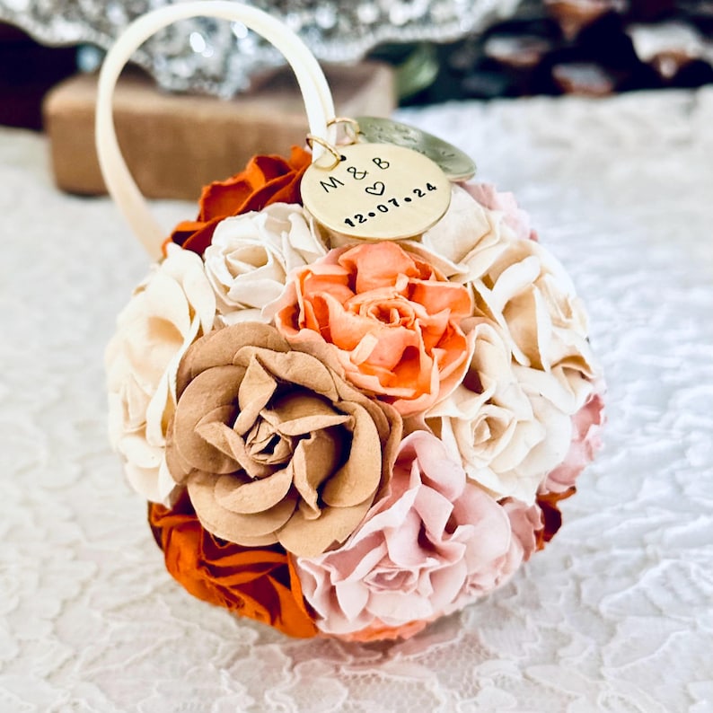 a 1st anniversary ornament made from paper flowers in custom shades of ivory, blush, peach, clay, and terra cotta.  The Christmas ornament has 2 custom charms, engraved with "one year" anniversary and a couples' initials and wedding date.