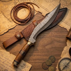 May include: A handcrafted knife with a curved blade and wooden handle, resting on a wooden surface with a leather sheath. The blade has a detailed pattern, and the handle is adorned with brass accents. A leather cord and antique map are also visible.