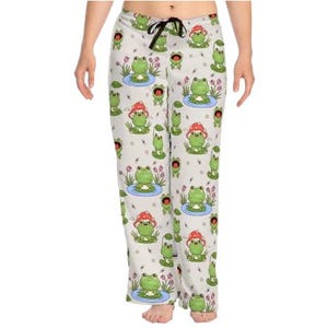 May include: Light grey pajama trousers with a repeating pattern of green frogs, some wearing red mushroom hats, and others in lily pads. The trousers have a drawstring waist and a relaxed fit, ideal for lounging.
