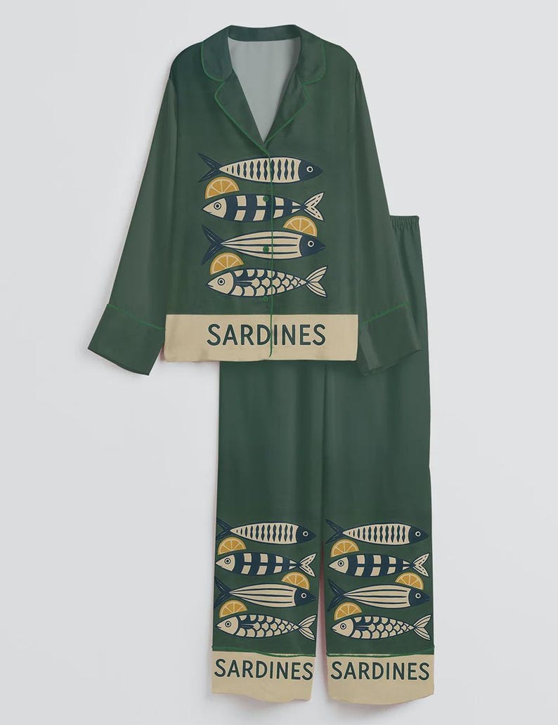 May include: Green pajama set with a collared top and matching pants. The set features a repeating pattern of stylized fish with lemon slices. The word "SARDINES" is printed on the top and bottom of the set.