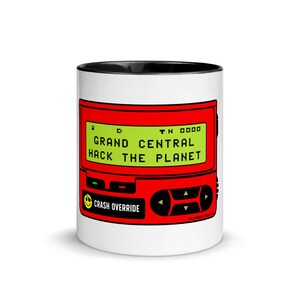 May include: White ceramic mug with a black rim. The mug features a red and green illustration of a retro-style pager with the text "Grand Central Hack The Planet" on the screen.