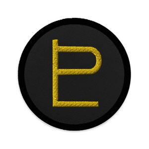 Op de afbeelding: Een geborduurde zwarte en gouden patch met een gestileerde letter 'P' in het midden.