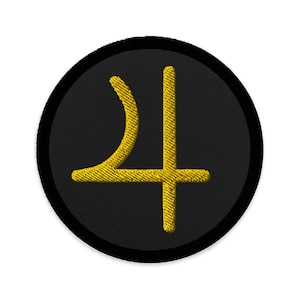 Könnte beinhalten: Ein gestickter schwarzer und goldener Aufnäher mit dem astrologischen Symbol für Saturn.