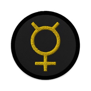 May include: A black and gold embroidered patch with the symbol for the planet Venus.