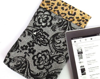 May include: A black and white floral patterned e-reader case with a leopard print trim. The case is shown with an e-reader displaying a list of books in French.