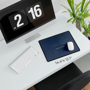 May include: A computer desk setup featuring a monitor displaying 2:16 PM, a white keyboard, and a mouse. A blue mousepad with the text "NEURAL CORE" and dimensions of 14.4" x 12.1" is also present.