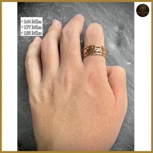 Puede incluir: Un anillo de color cobre con un diseño texturizado se lleva en un dedo. El anillo tiene un patrón repetitivo. El texto en el lado izquierdo dice "144 Mhz", "177 Mhz" y "188 Mhz". El anillo es una joya.