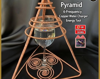 Könnte beinhalten: Eine Kupferpyramidenstruktur mit einem Glas Wasser im Inneren. Die Pyramide besteht aus verdrilltem Kupferdraht und hat eine dreieckige Basis. Der Text auf dem Bild lautet "Pyramide 6-Frequenz Kupferwasser-Ladegerät Energiewerkzeug".