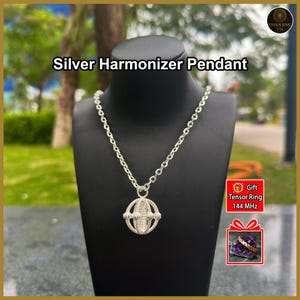 May include: A silver Harmonizer pendant on a matching silver chain. The pendant features a spherical, cage-like design with twisted metal wire detailing. The image includes text reading Silver Harmonizer Pendant and Gift Tensor Ring 144 MHz.