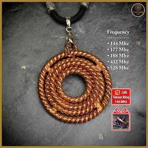 Pode incluir: Um colar com pingente de cor cobre com um design circular trançado. O pingente pende de um cordão preto com detalhes prateados. O texto na imagem lista as frequências: 144 Mhz, 177 Mhz, 188 Mhz, 432 Mhz e 528 Mhz.