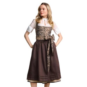 May include: A dirndl dress featuring a white blouse with short sleeves and a high neckline. The bodice is patterned with a brown and black leopard print, complemented by a matching leopard print sash tied at the waist over a solid brown skirt.