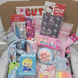 May include: A gift box filled with various stationery and accessories. Items include Hello Kitty stickers, pencils, a blue headband, a small building block set, and a variety of other pink and blue items. The box is open, revealing the contents.