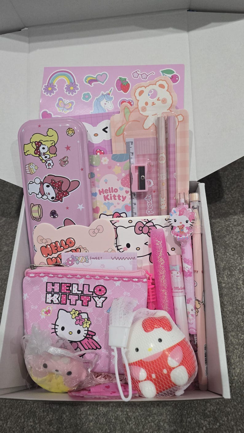 May include: A pink Hello Kitty themed gift box filled with stationery items. Includes a pencil case, pencils, pens, a ruler, a pencil sharpener, and stickers. The box is filled with pink and white items.