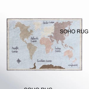 May include: A rectangular rug featuring a world map design. The map is in shades of brown and beige against a light blue background. The oceans are labeled, and the text "SOHO RUG" is visible. The rug has a border.
