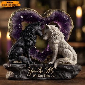 May include: A decorative sculpture featuring two wolf figurines facing each other, one black and one white, set against a purple heart-shaped amethyst geode. The base reads "You & Me We Got This" with the names "Charlie" and "Sophia" below the wolves.