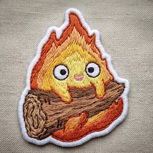 May include: A white ceramic mug with a black handle and the text "But First, Coffee" in a bold, black font. The mug is set against a blurred background, highlighting its clean design.