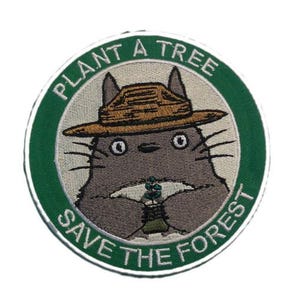 May include: Embroidered patch featuring a cartoon character wearing a ranger hat and holding a small plant. The patch is circular with a green border and text that reads "PLANT A TREE" and "SAVE THE FOREST" in white.