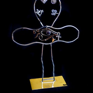 K&ouml;nnte beinhalten: Ein silberner Ankh-St&auml;nder aus Metall mit einem violetten Stein-Horusauge und einem goldenen Ankh-Anh&auml;nger. Der St&auml;nder hat eine goldene Basis und ist mit kleinen silbernen Anh&auml;ngern verziert.